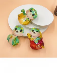 Three green cartoon snake hair claws with a red blessing bag for the 2025 Lunar New Year