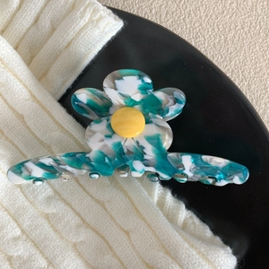 Détail macro d'une pince à cheveux fleur en acétate avec marbrure verte blanche et cœur jaune