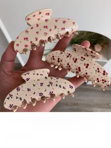 Close-up of floral acetate hair claws with cherry patterns and rhinestone detailing