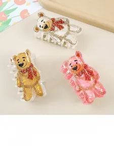 Close-up of bear-shaped hair claws in white yellow and pink with red polka dot bows