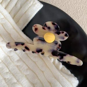 Détail d'une pince à cheveux fleur en acétate crème avec motif écaille sur tricot