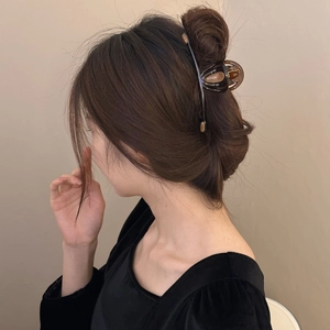Caramel brown shark hair claw clip in a minimalist curved design on long dark hair