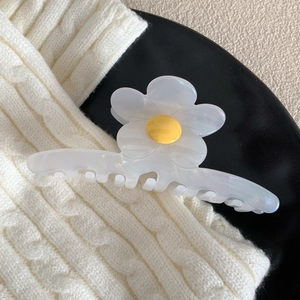 Gros plan d'une pince à cheveux en fleur d'acétate blanche avec un cœur floral jaune