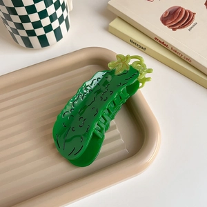 Detail shot of a cucumber-shaped hair claw clip with glossy green texture and vine accents