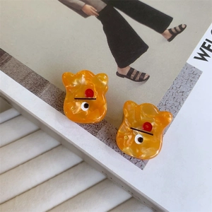 Orange marble pattern cat-shaped acetate hair claw clips displayed on a fashion magazine