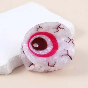 Acetate hair claw clip featuring unique evil eye design with red iris on stone display