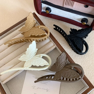 Matte butterfly hair claws in cream, mocha, and black on a vintage aesthetic background
