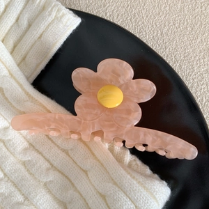 Gros plan d'une pince à cheveux fleur en acétate rose avec texture marbrée et centre jaune