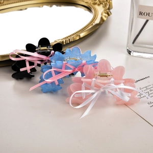 Détail de trois pinces à cheveux style ballet avec rubans en noir, bleu et rose pastel
