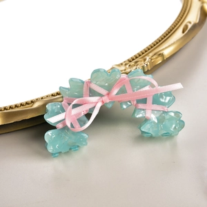 Vue détaillée d'une pince à cheveux en acétate bleu clair avec ruban rose sur miroir