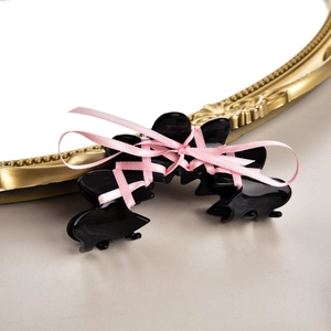 Détail d'une pince à cheveux noire avec ruban rose style ballet et design à lacets