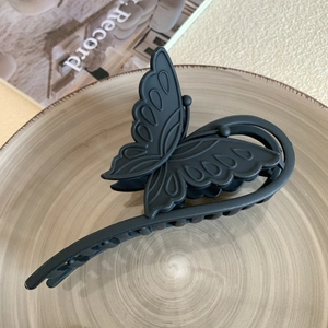Close-up of black matte butterfly hair claw clip with hollow carved wing texture