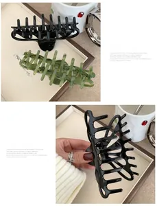 Macro detail of large glossy black and green marble acetate hair claws with gold logo