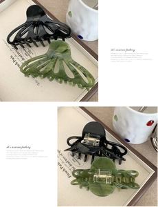 Detail view of glossy black and olive marble acetate hair claws with France gold lettering