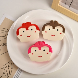 Détail de trois pinces à cheveux singe mignonnes en rouge, marron et rose sur plat blanc