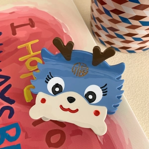Dettaglio della molletta per capelli a drago blu e beige in acetato con segno Fu d'oro