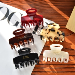 Pinces à cheveux en acétate style français, coloris rouge, ambre et marbre sur magazine