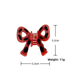 Detail view of red bow hair claw clip with black dots and dimensions of 5.3cm width