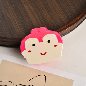 Détail d'une pince à cheveux singe rose en acétate lisse au design cartoon
