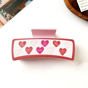 Detailansicht der rosa Haarklammer mit Herzmuster, XOXO-Print und roten Texturkanten