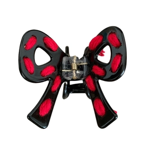 Minimalist black acetate bow hair claw clip with red knitted wool accent on white background