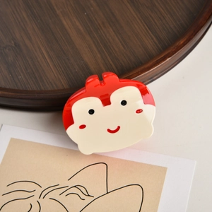 Détail de la pince à cheveux singe rouge et crème en acétate sur support en bois