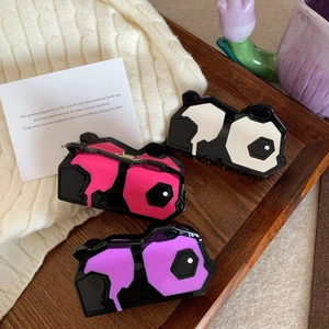 Schicke schwarz-weiße Panda-Haarklammern aus Acetat auf Holztablett mit Strickhintergrund