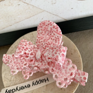 Détail d'une pince à cheveux en acétate rose et blanc sur un plateau en marbre
