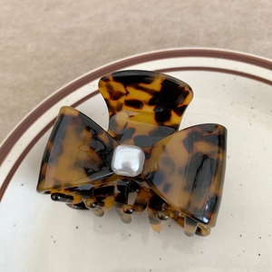Detail of tortoise shell acetate hair claw clip with bow shape and square pearl accent