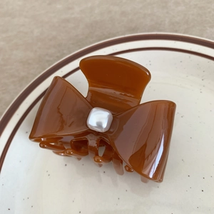 Close-up of caramel brown acetate hair claw clip with a square white pearl bow detail