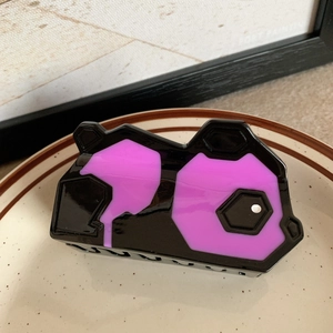 Detail einer geometrischen schwarz-lila Panda Haarklammer auf einer Keramikschale
