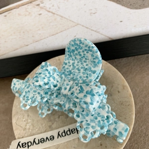 Détail de la pince à cheveux en acétate à motif bleu et blanc avec design de nœud évidé