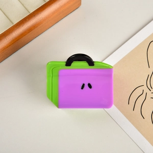 Dettaglio di un fermaglio per capelli in acetato viola a forma di borsa con finitura lucida