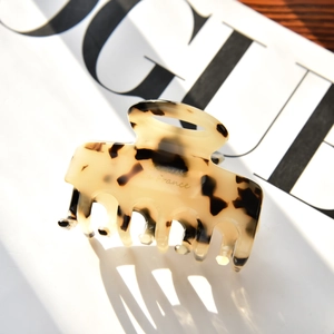 Détail de la pince à cheveux en écaille avec marquage doré sur un magazine de mode