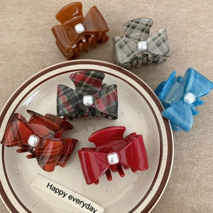 Elegant acetate bow hair claws with square pearls in multiple colors on ceramic plate