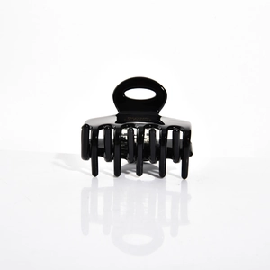 Détail du clip à cheveux en acétate noir brillant montrant le logo doré Barrette France