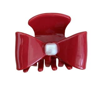 Elegant red bow hair claw clip with glossy finish and central pearl detail