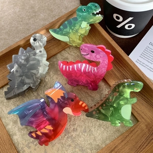 Niedliche Haarklammern aus Acryl in Dinosaurierform in fünf Farben auf Holztablett