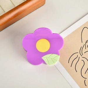 Dettaglio della molletta per capelli a fiore viola con centro giallo e foglia verde