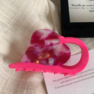Dettaglio della pinza per capelli a forma di cuore in acetato rosa marmorizzato