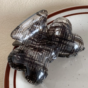 Detail of elegant large acrylic hair claw with black plaid pattern in butterfly shape