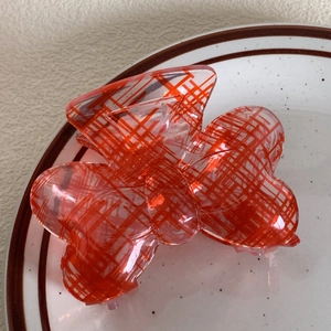 Macro shot of a butterfly hair claw clip with red grid patterns on transparent acrylic
