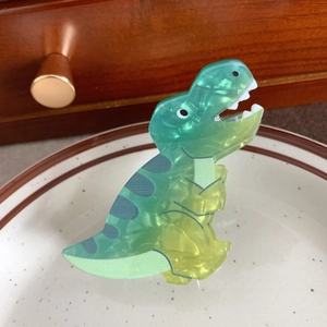 Detailansicht einer T-Rex Haarspange aus Acetat auf einem eleganten Keramikteller präsentiert