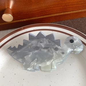 Detailansicht der Stegosaurus-Haarklammer mit Marmortextur und Glitzer-Akzenten