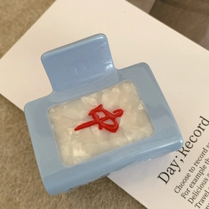 Gros plan sur une pince à cheveux Mahjong bleue et blanche avec motif rouge chinois