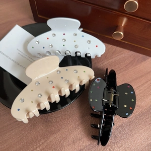 Acetate hair claw clips in white and black with colorful rhinestones in a luxury setting