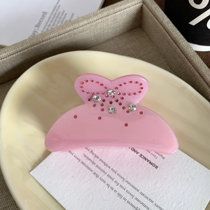 Detailaufnahme der rosa Haarklammer aus Acetat mit glitzernden Strasssteinen im Schleifen-Design