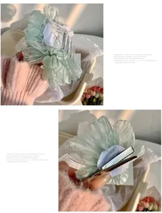 Détail d'un ensemble de pince à cheveux et barrette à fleur en organza vert clair