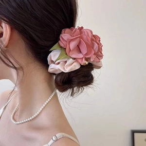 Chouchou élégant avec grande fleur rose en soie et perle dorée sur un chignon haut