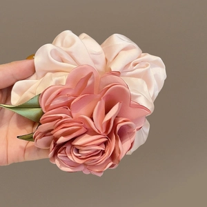 Vue détaillée du chouchou rose 3D avec pétales en satin rose et feuilles vertes